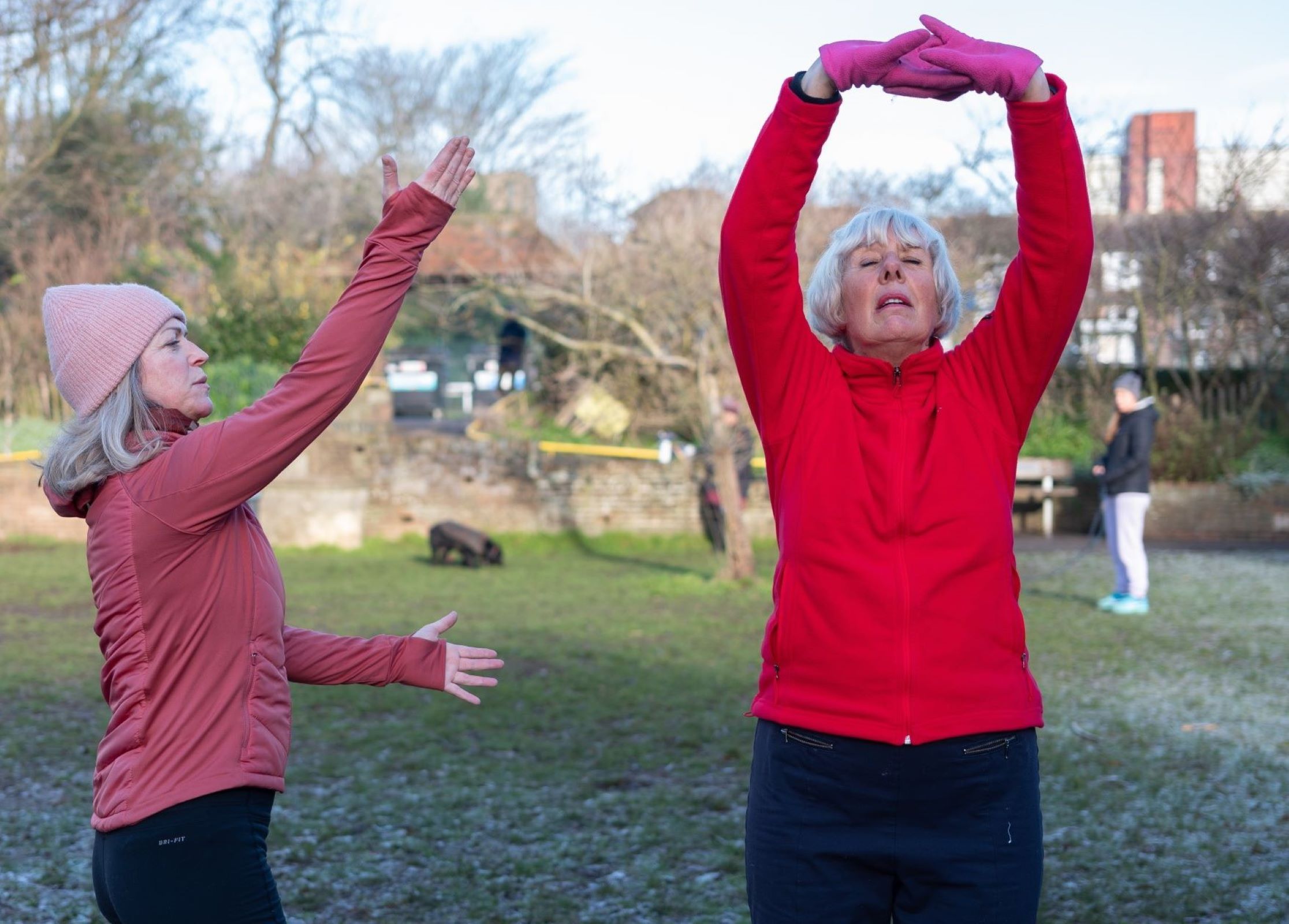 People stretching in a park wearing hats and gloves